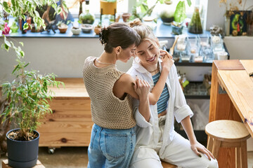 Loving lesbian couple sitting closely, sharing creative moment in art studio.