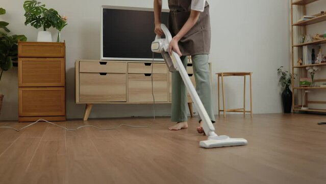 a wife is doing housework, use cleaning tools to make cleaning the floor easier, housekeeper is trying to remove dust on the floor because it is dirty, maintain hygiene within the house