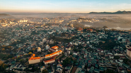 Aerial view of Dalat City at sunrise, showcasing urban landscape amidst natural beauty, buildings...