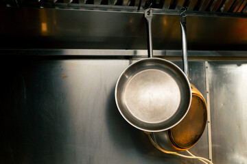 close-up in professional kitchen two frying pans weigh on a wall holder for frying food