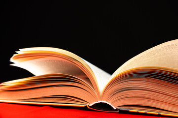 Pages of a thick book are turned on a red and black background.
