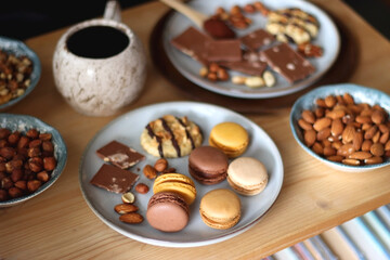 Cup of tea or coffee, cookies, macaroons, chocolate, various nuts and cocoa powder on wooden table. Selective focus.