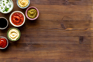 Set of bowls with sauces pesto salsa mustard and others, top view. Food background
