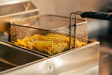 close-up in professional kitchen there are ready-made French fries on the deep fryer