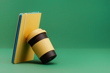 Reusable cup with rubber lid is leaning on the yellow book on a green background. The concept of an...