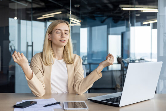 Professional woman meditating at desk in modern office