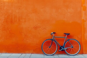 city bicycle standing at new orange color wall, outdoors, evening 