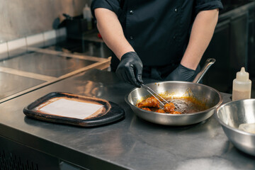 close-up in a professional kitchen the chef puts ready-made chicken wings on wooden tray