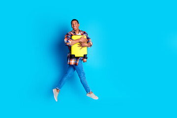 Full size photo of nice young man hold suitcase jump empty space wear shirt isolated on blue color background