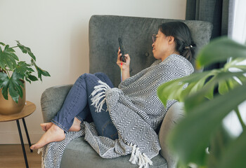 A asian young woman is playing with her phone on the sofa