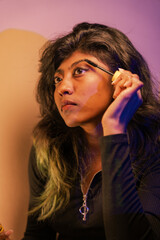 Obraz premium A woman is applying makeup, specifically mascara, to her eyes