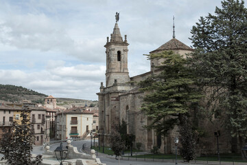 a historic church with a tall bell tower overlooking a quaint town square surrounded by buildings and trees