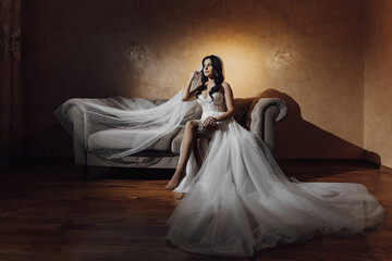 A woman in a wedding dress sits on a couch