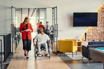 A business leader with her colleague, an African-American businessman who is a disabled person,...