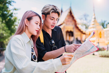 smiling tourist lover lost looking map finding way. happy asian lover unfolding map searching way...