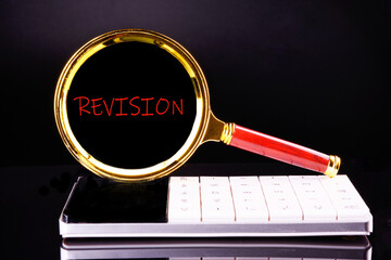 REVISION word written appeared through a magnifying glass on a black background standing on a...