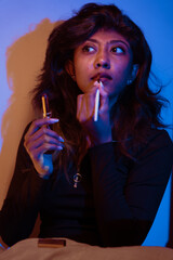 Fototapeta premium A woman is applying lipstick while holding a lipstick tube