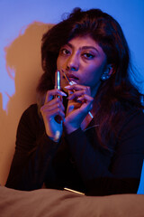 A woman is holding a cigarette and a tube of lipstick