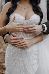 A bride and groom are embracing each other, with the bride wearing a white dress and the groom wearing a black suit. Concept of love and happiness