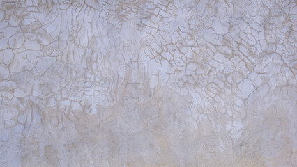 The old grunge concrete fence wall background with abstract pattern of many crack lines and stains on surface