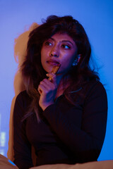 A woman is sitting in a room with a blue background