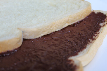 Two slices of white bread with chocolate spread or chocolate jam. Chocolate sandwich. On white plate, isolated on white background
