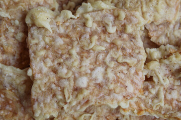 Background texture of Keripik tempe or tempeh crackers, square shape. Thin slices tempeh, fried with flour dough