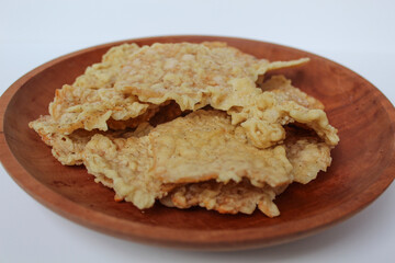 Keripik tempe or tempeh crackers, square shape. Thin slices tempeh, fried with flour dough. On wooden plate, isolated in white background