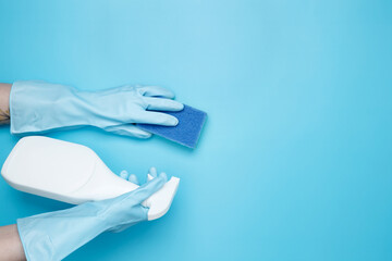 Womans hand in rubber glove holds yellow dishwashing sponge and cleaning product. House cleaning....