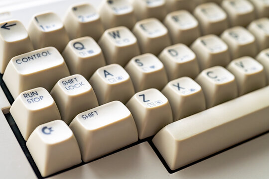 Close-up of vintage Commodore 64 keyboard with cream-colored keys and letters. Daylight illuminating the retro computer.