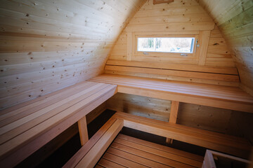 Interior view of a small cabin loft with wooden benches and a window, all surfaces covered in...