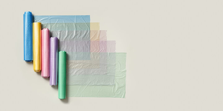 Colorful plastic bags in rolls as geometric pattern on beige background. Eco plastic product bio bags for food, Plastic free environment protection concept, eco trend to reduce disposable plastic