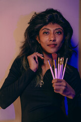 A woman is holding a bunch of makeup brushes in her hand