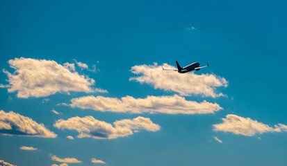 Fototapeta na wymiar Airplane taking off in blue sky with some clouds