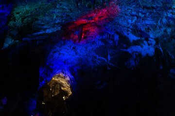Prometheus karst cave, illuminated by colorful lights, stalactites and stalagmites.