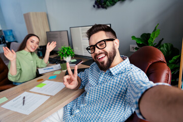 Photo of positive good mood employers dressed shirts showing v-signs tacking selfie indoors...