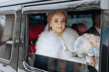 A bride is sitting in a car with a bouquet of flowers. She is wearing a white fur coat and a tiara