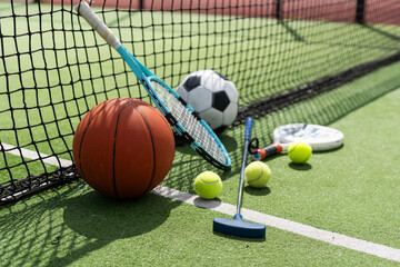 A variety of sports equipment including an american football, a soccer ball, a tennis racket, a...