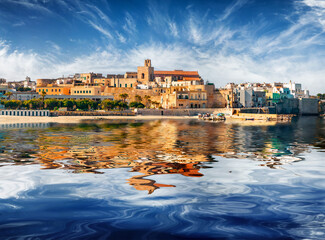 Ancient buildings of Otranto town reflected in the calm waters of Adriatic sea. Sunny morning scene...