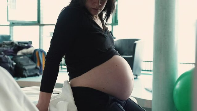 Pregnant woman seated by bedside at hospital during pre labor contractions. third trimester pregnancy before childbirth