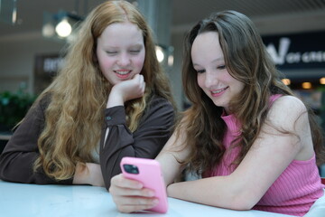 Close up of two young girls looking at smartphone playing mobile games, chatting in social media