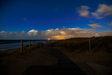 Dunes on the beach near the Pettendorf Monument in the Netherlands at night with a full moon