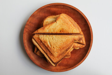 Some toasts or toasted breads, on wooden plate, isolated on white background, flat lay or top view