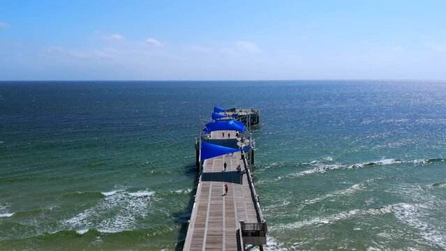Serene and beautiful view of Pompano Beach and pier leading to establishment with blue roofs. Picturesque scene capturing essence of relaxing and enjoyable day at ocean