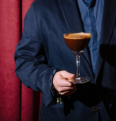 Man in suit holding espresso martini cocktail