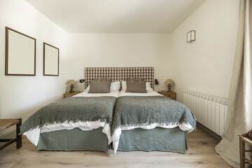 A bedroom with twin beds pushed together with fabric upholstered headboards, blankets and duvets...