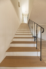Staircase with oak wood steps of a single-family home with black minimalist style metal railing