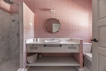 A beautiful modern designed bathroom with cream marble sink, gold wooden framed mirror, matching...