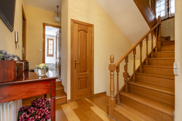 Interior staircase of a single-family home with a landing with a wooden sideboard with oak wood...