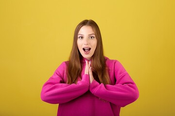 Surprised attractive female with long hair in trendy pink hoodie posing indoor. Millennial girl...